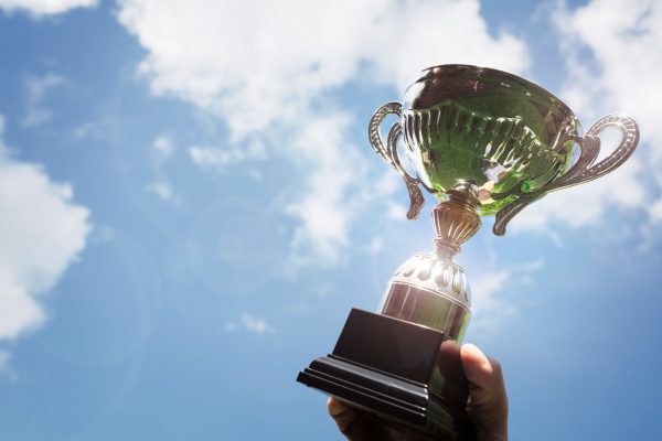 holding-up-a-trophy-cup-as-a-winner-PXJD3UQ_resize_envato