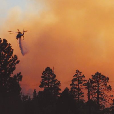 a-helicopter-dumps-water-on-a-forest-fire-JCHSS3E