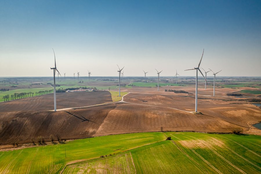 aerial-view-of-wind-turbines-on-green-field-sunny-2023-11-27-04-52-23-utc